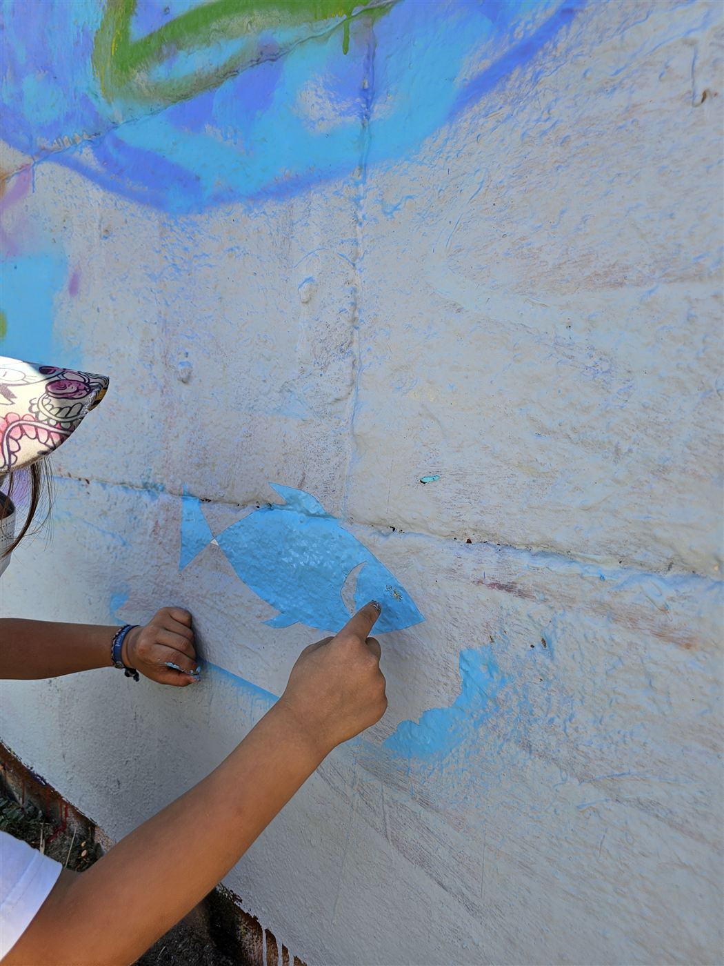 Participant réalisant un motif bleu au pinceau lors d'un atelier street art YAP à Sète