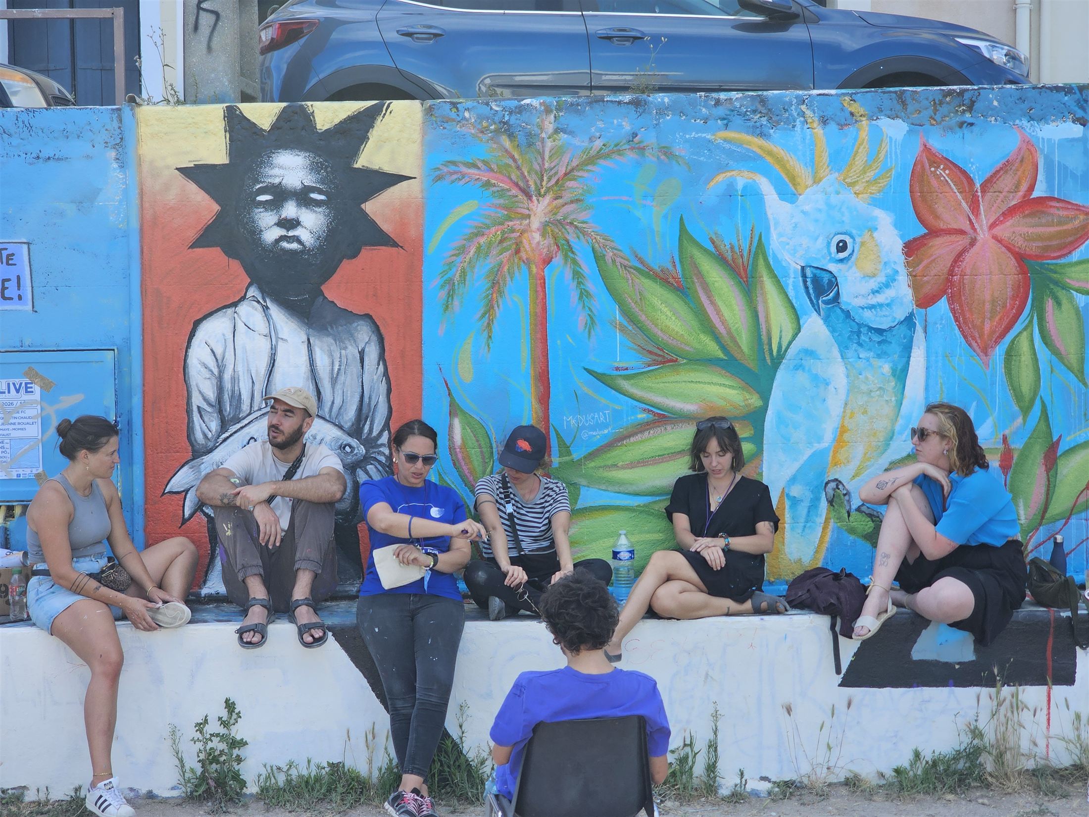 Artistes et participants devant une fresque colorée à Sète, juin 2026